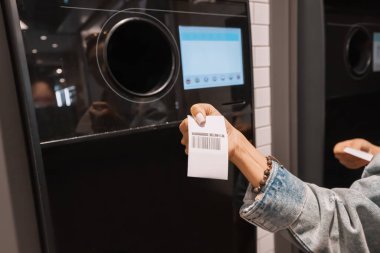 Öğrenci bir kız otomatik makineye geri dönüşüm için plastik bir içecek şişesi veriyor ve süpermarket için avro çeki indirimi yapıyor. Çevre dostu yaşam tarzı ve nakit para