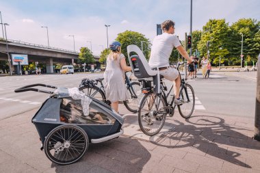 30 Temmuz 2022, Köln, Almanya: Bir spor ailesi - çocuk sahibi bir anne ve baba eski bir Avrupa şehrinin sokaklarında bisiklet sürüyor