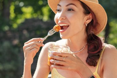 Mutlu bir kız, açık kafede baharatlı, geleneksel Alman baharatlı, sulu sosisi yer.