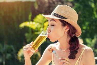 Geleneksel biergarten 'de bira içip geleneksel Alman sosisi yiyen mutlu susamış kız. Ulusal mutfak ve içecek.