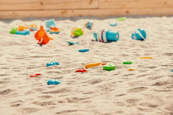 Toys are scattered in a large children\'s sandbox. Childhood and leisure of kids