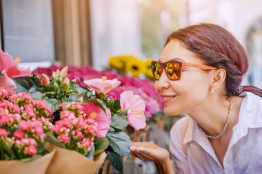 Bir kız alıcı ve bir müşteri, marketteki saksılarda buket ve çiçekleri ve şehir sokaklarındaki çiçekçi dükkanını seçiyor.
