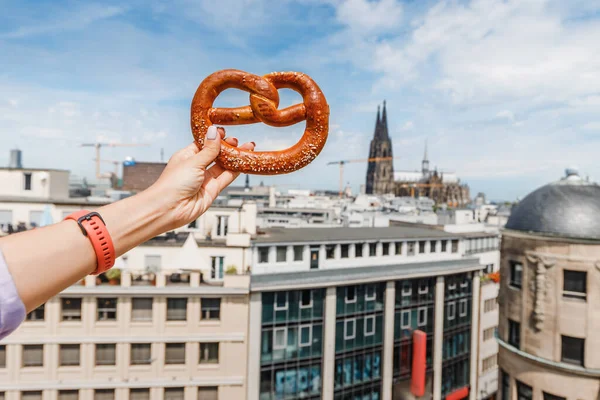 Touristenhand Mit Traditionellem Brezelvesper Vor Dem Hintergrund Eines Kölner Domgebäudes — Stockfoto