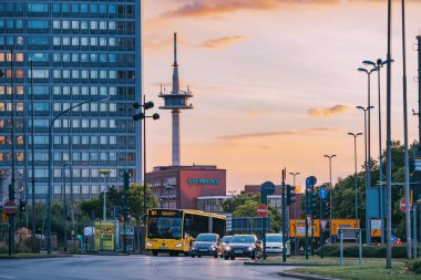 28 Temmuz 2022, Essen, Almanya: Essen 'in canlı bir bölgesinde arabaları, otobüsleri ve cam gökdelenleri olan ve ticari gayrimenkulleri olan bir sokak. Arkaplanda TV kulesi olan günbatımı