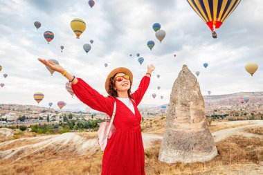 Elbiseli bir kız, Cappadocia 'da uçan sıcak hava balonlarının nefes kesici görüntüsüne daldı. Gezgin cenneti..