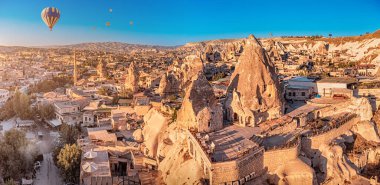 Cappadocia 'da oyulmuş evler ve oteller arasında pürüzsüz uçan ve yüzen sıcak hava balonlarının manzaralı panoramik manzarası