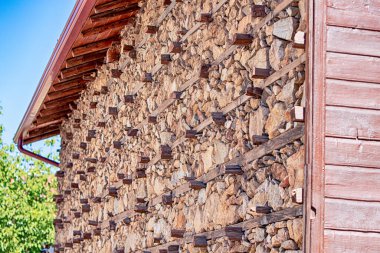 Dağların tepesinde taştan ve ahşaptan yapılmış düğmeli bir ev duvarı.