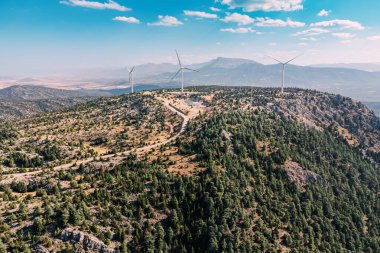 Düzinelerce rüzgar türbininin enerjisiyle parlayan bir dağın muhteşem panoramik manzarası nefes kesici, güzel bir manzara yaratıyor..