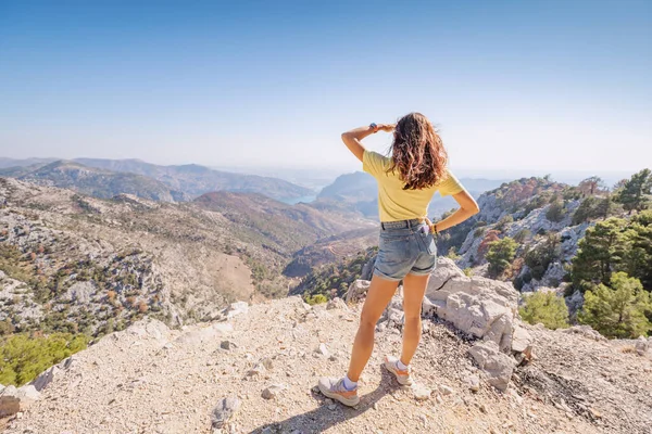 Dağ kanyonunun görkemli manzaralı manzarasında kot şort giyen kız.
