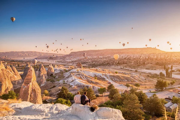Friends Sitting Clifftop Viewpoint Admiring View Majestic Flying Hot Air — Stock Photo, Image