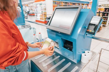 Süpermarketteki otomatik self-servis kasası müşterilerin kasiyere ihtiyaç duymadan eşyalar için hızlıca tarama ve ödeme yapmalarına olanak sağlıyor..