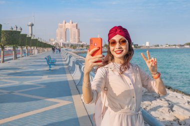 BAE 'nin başkentinde modernlik ve ilerleme ruhunu somutlaştıran bir kız, Abu Dabi' nin göz kamaştırıcı siluetine karşı bir fotoğraf çekiyor.