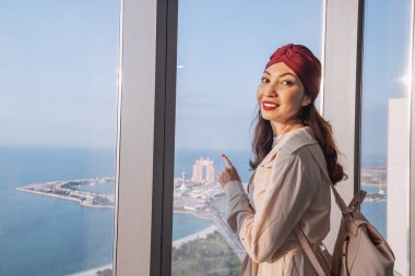 Gözlem noktasındaki kız turist yatları ve yolcu gemileriyle Abu Dabi şehir limanına bakıyor.