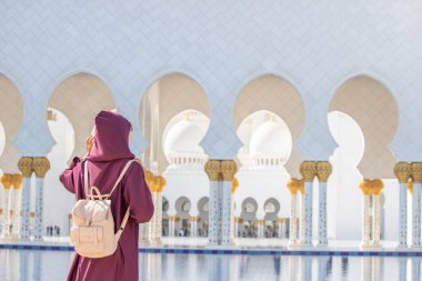 Akan bir Abaya 'nın içinde giyinmiş genç bir turist kadın Abu Dabi' deki Şeyh Zayed Büyük Camii 'ne doğru bir yolculuğa çıkıyor..
