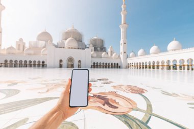 Boş ekran akıllı telefonlu el ve Abu Dabi 'deki Şeyh Zayed Büyük Camii. Wi-fi internet ve elektronik bilet.
