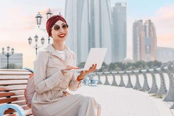 In the heart of the city that blends traditional and modern, a student or freelancer girl works on her laptop, taking advantage of the UAE\'s progressive approach to remote work and education.