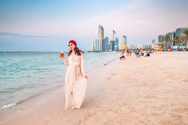Glückliches Mädchen Sandstrand Mit Kaffee Zum Mitnehmen Hintergrund Wolkenkratzer Abu — Stockfoto