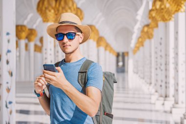 Sırt çantalı bir turist Abu Dabi 'deki Şeyh Zayed' in Büyük Camii 'ne giriş bileti almak için cep telefonu kullanıyor.