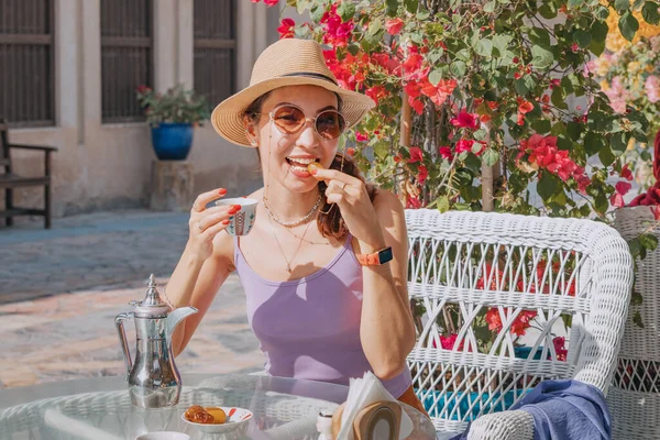 As she sits in a traditional cafe in the UAE, a girl sips on fragrant Arab coffee and nibbles on sweet dates, immersing herself in the rich culture and history of the region.