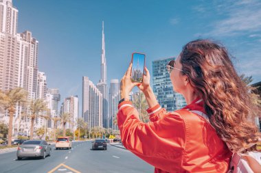Seyahat blogu için fotoğraf çeken turist mutlu kız, Dubai şehir merkezinde Burç Halife 'nin en yüksek gökdeleninin arka planında