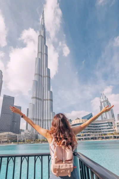 Dubai, BAE 'deki gerçek dışı Burj Halife kulesiyle inanılmaz manzarayı kucakladığı için mutlu bir kızın kollarının dikey görüntüsü açılır.