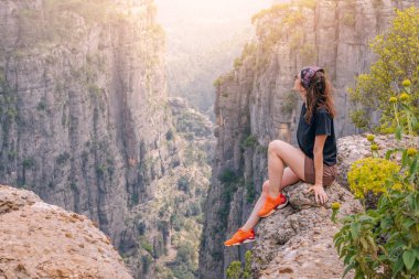 Türkiye 'deki Tazi Kanyonu' nun tepesinde oturan mutlu gezgin kız. Turistik yerler ve turistik yerler