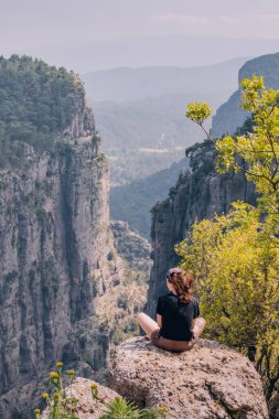 Türkiye 'deki Tazi Kanyonu' nun tepesinde oturan mutlu gezgin kız. Turistik yerler ve turistik yerler
