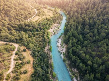 Derin kanyondaki gök mavisi kıvrımlı nehrin havadan görünüşü sakin ormanlarla çevrili.