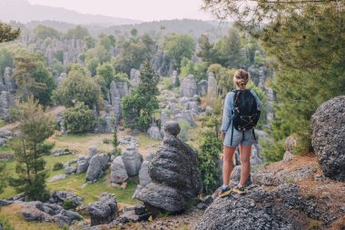 Altinkaya, Türkiye 'deki kayalıkların tepesinde taş kalıntılarını gören mutlu gezgin kız. Turistik yerler ve turistik yerler