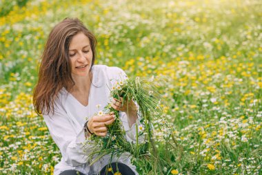 Mutlu kız, doğal çayırlarda papatya çiçeği yapıyor.
