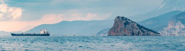 Kargo gemisi ve dağlarla panoramik deniz manzarası