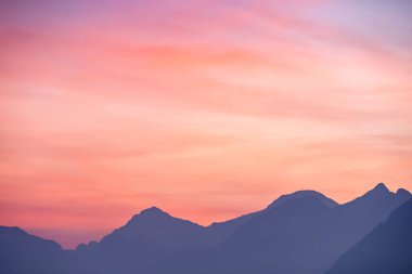 Mor ve pembe gökyüzü sisli dağların üzerinde