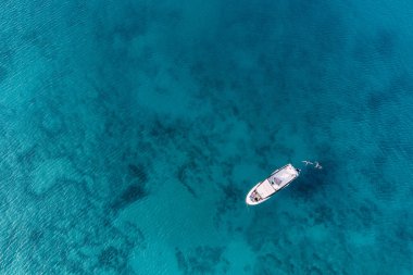 Tatilcilerin olduğu bir yat manzarası ve altında desenler olan görkemli mavi deniz.