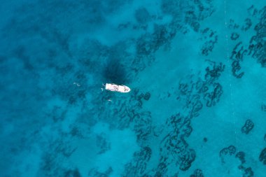 Tatilcilerin olduğu bir yat manzarası ve altında desenler olan görkemli mavi deniz.