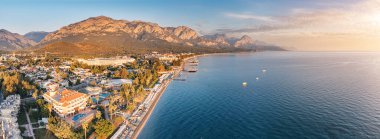 Kemer 'in büyüleyici manzarası, otellerin, güzel bir sahil sahilinin ve görkemli dağların birleştiği göz kamaştırıcı bir hava fotoğrafı ile büyüleyici bir cazibe..