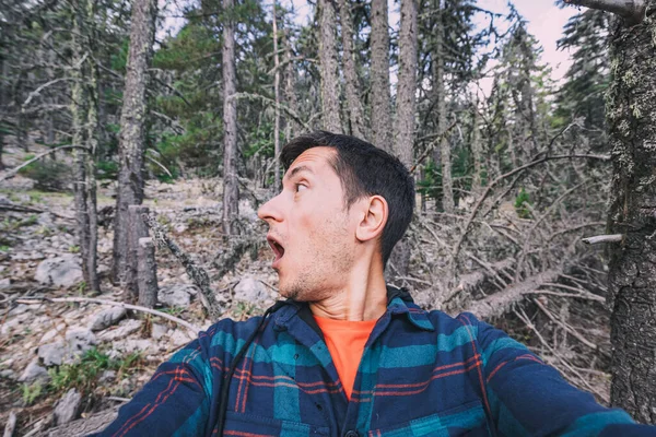 stock image A frightened and lost male hiker looks around in the forest. The concept of meeting wild animals and phobia and accident in the woods