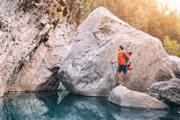 一个快乐的徒步旅行者 他背着背包在深峡谷中一条风景秀丽的溪流河岸上的山路上走着 或在峡谷里堆满了巨石和巨石 — 图库照片