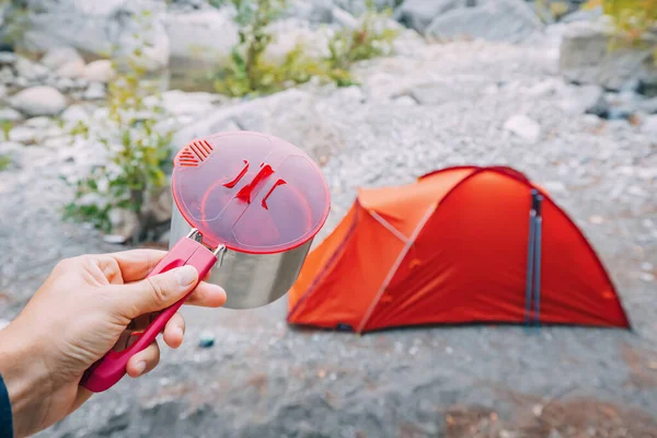 Stock image camping food - metal pot on the background of a tent in wild camping. Hiking cookware and tableware