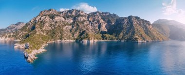 Aerial view of mesmerizing beauty of the Lycian Way on the sea coast in Turkey during sunset. Scene unfolds with majestic mountains bathed in the warm hues of the setting sun.