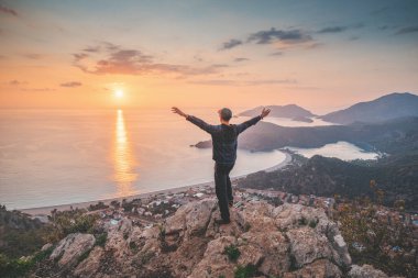 Happy man admiring view of a scenic sunset over Oludeniz town in Turkey. Lycian Way travel sights