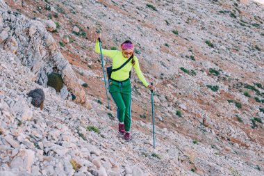 Conquering Heights: Bir kadın dağcı açık hava riskini kucaklıyor, aktif bir macera gösterisi olarak yüksek kayalara ve kayalıklara tırmanıyor.