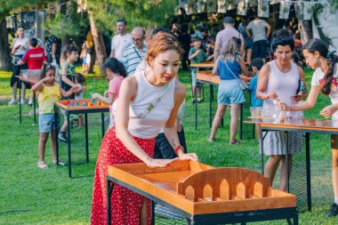 01 Temmuz 2023, Antalya, Türkiye: Yaz Oyunları: Parti kentinde oynanan masa üstü oyununda insanların eğlenmesi için ahşap masa sahnesi haline geldi