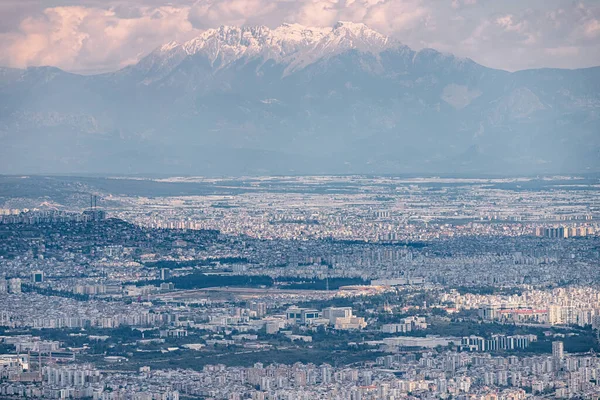 Kentsel Vista: Bir şehir manzarası çarpıcı gökyüzünün arkaplanına karşı gökyüzünü gözler önüne seriyor, büyüleyici bir manzarayla mimari ve dağları harmanlıyor.