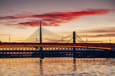 Sırbistan 'ın Belgrad kentindeki Sava Nehri üzerinde muhteşem bir günbatımı, Köprü' yü aydınlatıyor ve kentsel manzarayı altın bir ışıltıyla donatıyor.