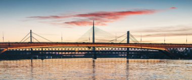 Sırbistan 'ın Belgrad kentindeki Sava Nehri üzerinde muhteşem bir günbatımı, Köprü' yü aydınlatıyor ve kentsel manzarayı altın bir ışıltıyla donatıyor.