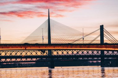 Sırbistan 'ın Belgrad kentindeki Sava Nehri üzerinde muhteşem bir günbatımı, Köprü' yü aydınlatıyor ve kentsel manzarayı altın bir ışıltıyla donatıyor.