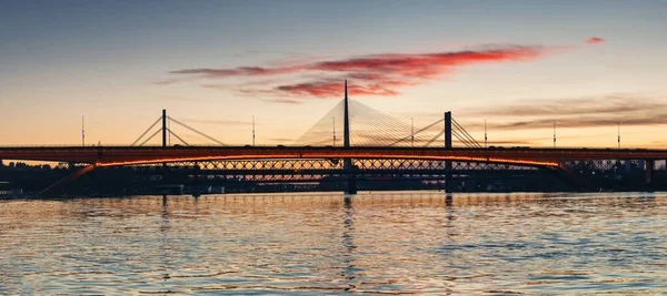 Sırbistan 'ın Belgrad kentindeki Savski Köprüsü, Sava Nehri' nin sakin sularını kaplayarak, modern mühendisliği akşam gökyüzünün arka planına karşı doğal güzellikle harmanlıyor..