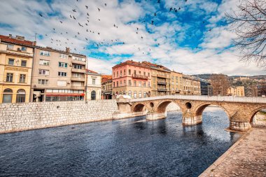 Saraybosna 'nın, tarihi caddeler ve modern binaların Miljacka Nehri boyunca birleştiği Latin Köprüsü' nden nefes kesici manzarası.