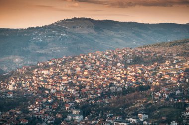 Güneş dalgalı tepelerinin ardında batarken Saraybosna manzarası şehrin üzerine renkli bir renk katıyor..