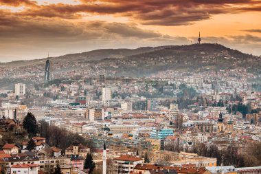 Güneş dalgalı tepelerinin ardında batarken Saraybosna manzarası şehrin üzerine renkli bir renk katıyor..
